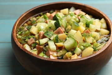 Delicious okroshka soup with kvass on blue wooden table, closeup