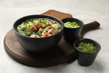 Delicious okroshka soup with kvass and ingredients on light table