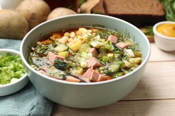 Delicious okroshka soup with kvass and ingredients on white wooden table, closeup