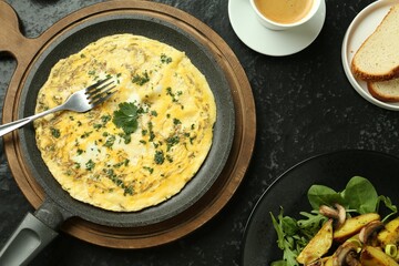 Tasty brunch. Delicious omelette, fried potatoes and coffee served on black textured table, flat lay