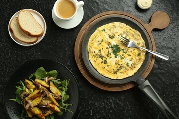 Tasty brunch. Delicious omelette, fried potatoes and coffee served on black textured table, flat lay