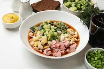 Tasty okroshka soup with kvass and ingredients on white marble table, closeup
