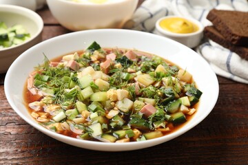 Tasty okroshka soup with kvass and ingredients on wooden table, closeup