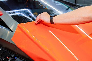 Vinyl wrap is being smoothly applied on surface of car for protect body automotive sleek, modern...