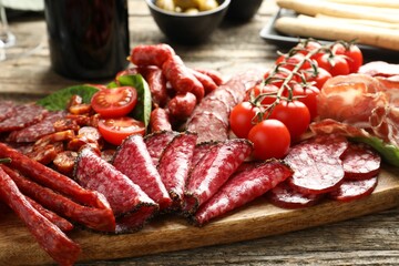Different smoked sausages and other snacks served on wooden table, closeup