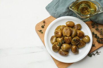 Delicious grilled green olives and oil on white table, flat lay. Space for text