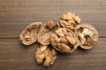 Fresh walnuts with shells on wooden table, flat lay
