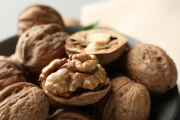 Fresh walnuts in bowl on light table, closeup