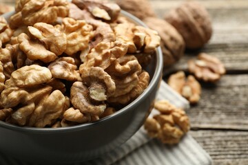 Fresh walnuts in bowl on wooden table, closeup