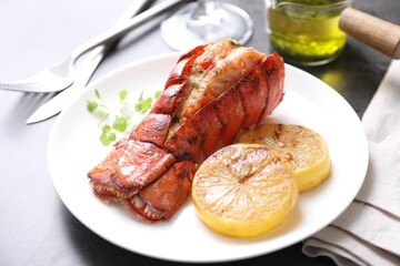 Delicious lobster tail with microgreens and slices of lemon on grey table, closeup