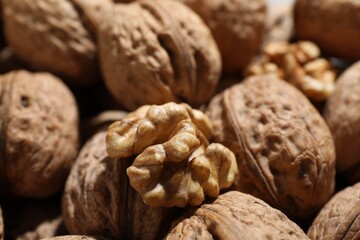 Fresh walnuts in shells and shelled one as background, closeup