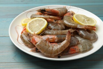 Fresh raw shrimps with lemon on light blue wooden table, closeup