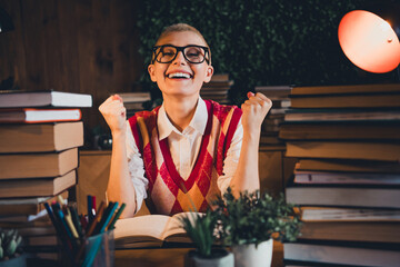Young woman with short blond hair, wearing a vibrant argyle waistcoat and glasses, studying...