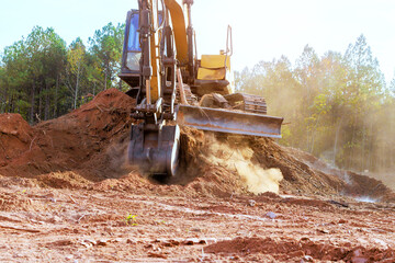Heavy excavator is actively moving dirt, debris at construction site surrounded by work equipment