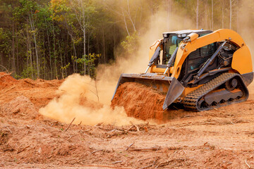 Heavy machinery clears land covered in dust among trees, preparing site for future development...