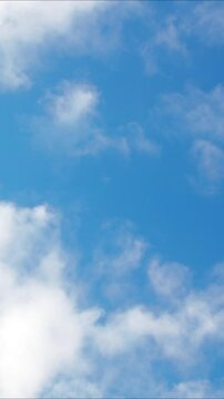 White clouds floating across the blue sky - vertical video. High quality 4k footage