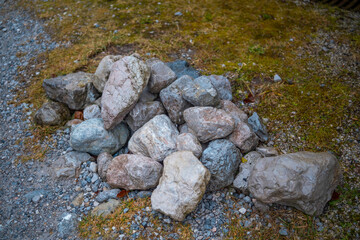 Pile of stones on a gravel path near green grass in a natural setting