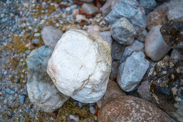 Natural stones of various sizes scattered on a gravel surface in the outdoors