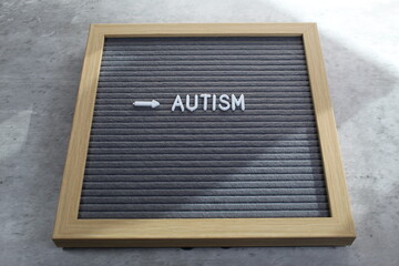 Autism written on a letter board with white tiles. Sunlight coming across