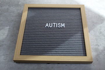 Autism written on a letter board with white tiles. Sunlight coming across