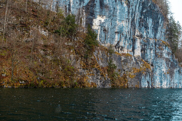 Majestic cliffside reflection in tranquil lake during a rainy day
