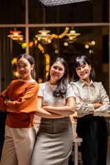 Fototapeta premium Three women are standing together, smiling and posing for a photo