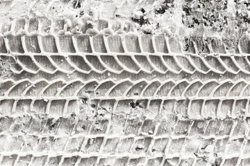 Snow tyre mark background. Asphalt covered in snow. Dangerous road conditions. Car imprint on frozen ground. Tire trail on ice. City streets covered in snow during heavy snow fall. Slippery mud under.