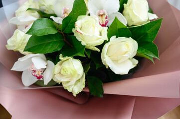 Bouquet of white roses and orchids in bottom packaging. Valentine's day and love concept