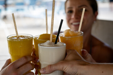 Colorful cocktails raised for a toast on a sunny day with friends. The vibrant drinks take focus,...