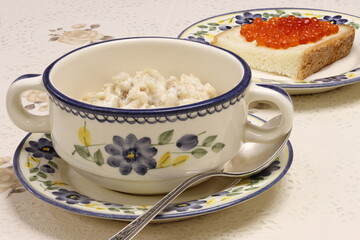 Breakfast. Oatmeal with milk and a sandwich with red caviar