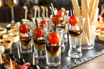 Many different tasty canapes on wooden table, closeup