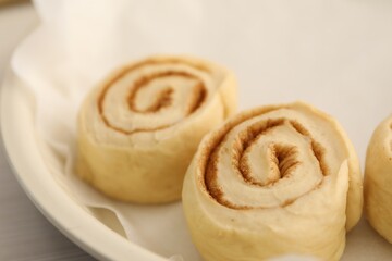 Uncooked cinnamon rolls in baking dish on table, closeup