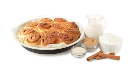 Freshly baked cinnamon rolls in baking dish and ingredients isolated on white