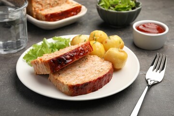 Delicious baked turkey meatloaf with potatoes served on grey table, closeup