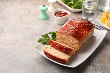 Delicious baked turkey meatloaf with vegetables served on grey table, closeup. Space for text