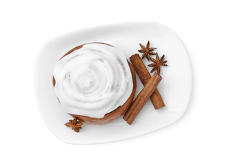 Tasty cinnamon roll with cream and spices isolated on white, top view