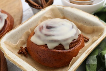 Tasty cinnamon roll with cream and spices in baking dish, closeup