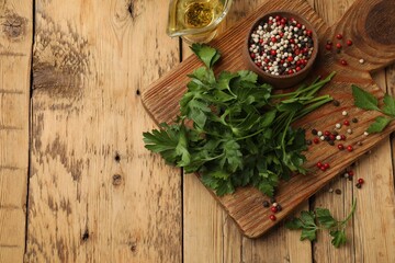 Fresh parsley, peppercorns and oil on wooden table, flat lay. Space for text