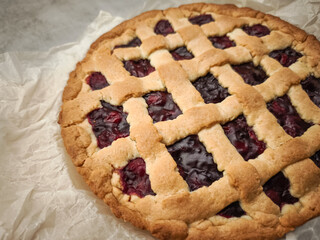 Homemade cherry pie cooling on rustic parchment, golden crust showcasing sweet seasonal filling