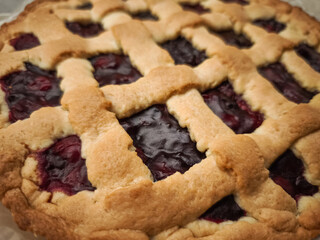 Homemade cherry pie featuring golden lattice crust, resting on rustic wooden surface near prague