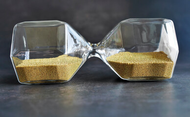 Close up laying sideway transparent Hourglass with golden Sand, sand glass in dark background, Time...