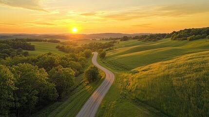 A long winding road through a lush green countryside at sunrise. 