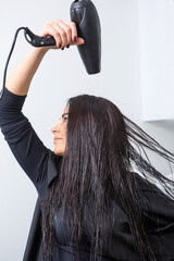 Fototapeta premium White woman blow drying her hair at home. Healthy hair.