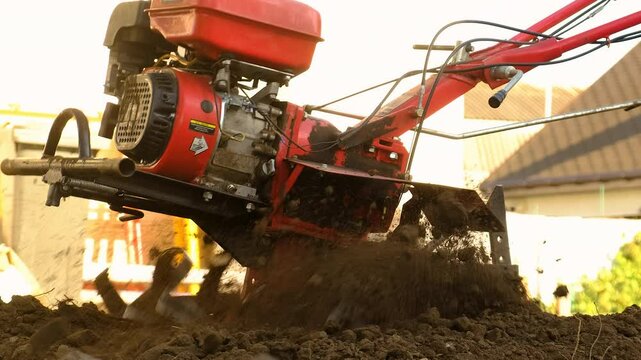 A man plows the land with a walk-behind tractor. Selective focus. Nature.