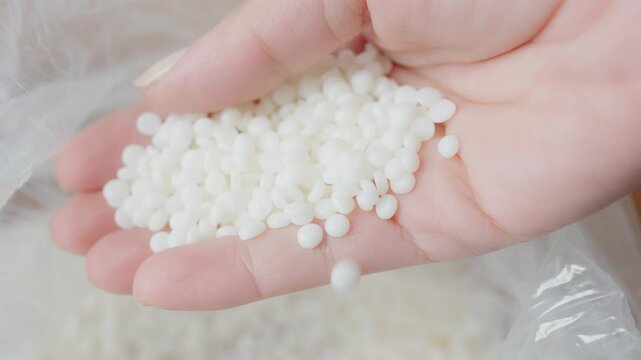 Hand Holding Small White Soy wax Pellets for Industrial or Craft Usage