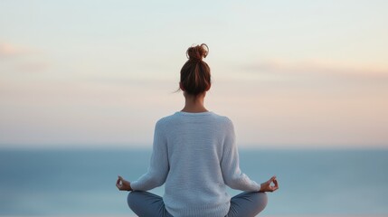 Pregnant woman sitting in a yoga meditation pose silhouetted against the serene backdrop of a tranquil beach at sunset  The image conveys a sense of inner peace harmony