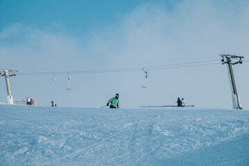 A skier enjoying a snowy day on the slopes under a clear sky with ski lifts.