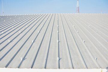 large metal roof with evenly spaced vertical ridges and small brackets or mounts attached at...
