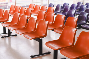 The seating arrangement in the public area consists of two rows of orange plastic chairs mounted on a black metal frame.