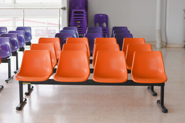 Fototapeta premium The seating arrangement in the public area consists of two rows of orange plastic chairs mounted on a black metal frame.